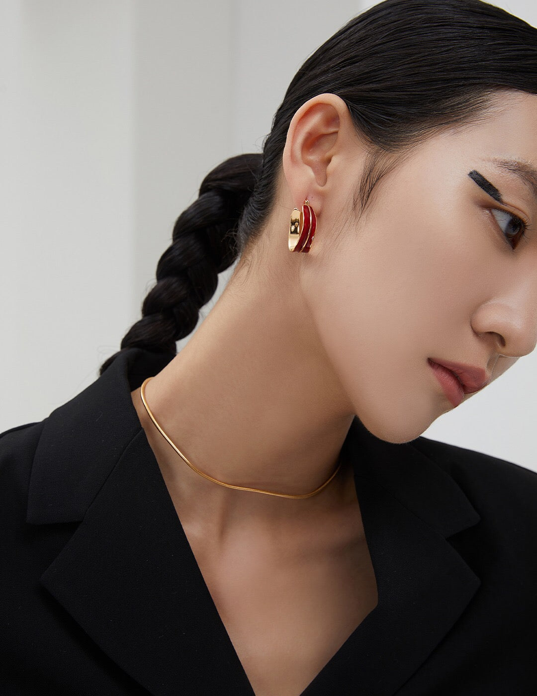 Model wearing Fernovia Design red drip‑glaze hoop earrings