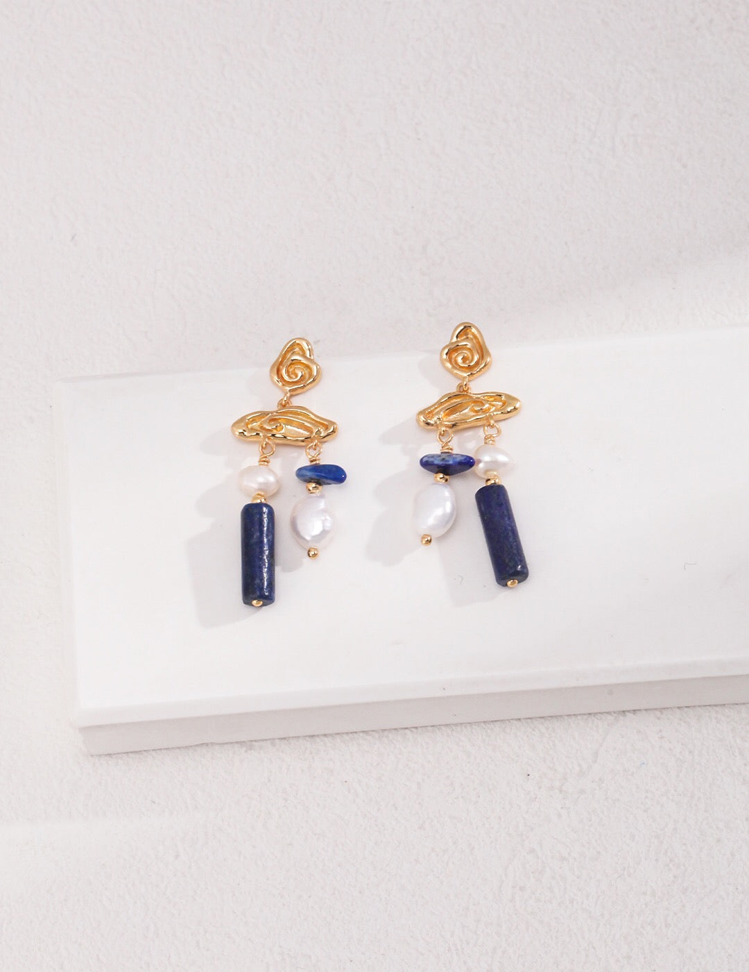 Blauer Lapislazuli-Edelstein mit Perlenohrringen