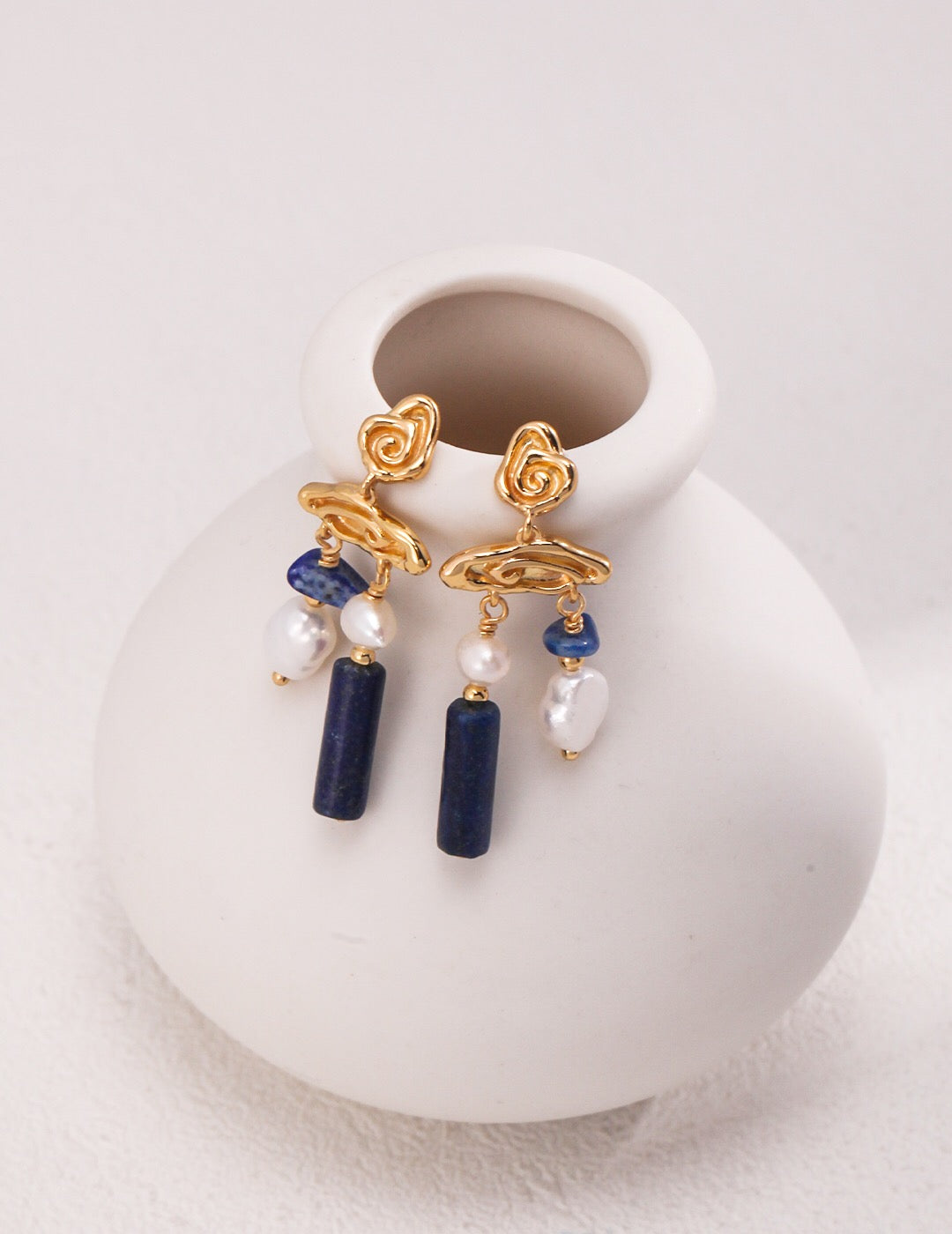 Blauer Lapislazuli-Edelstein mit Perlenohrringen