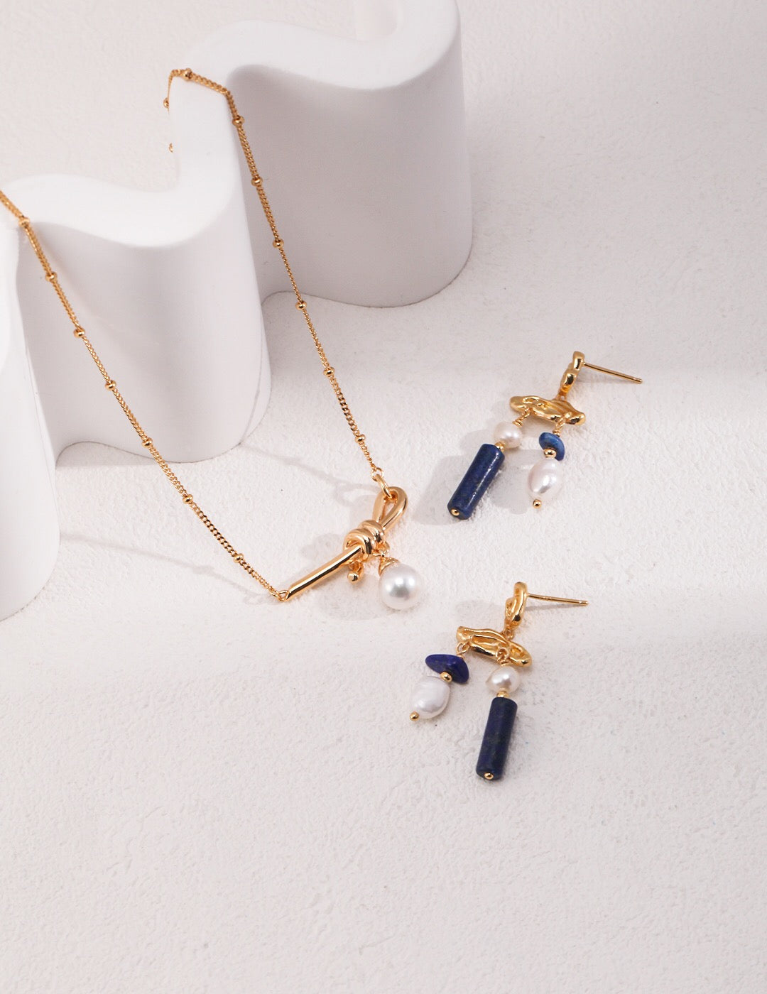Blauer Lapislazuli-Edelstein mit Perlenohrringen